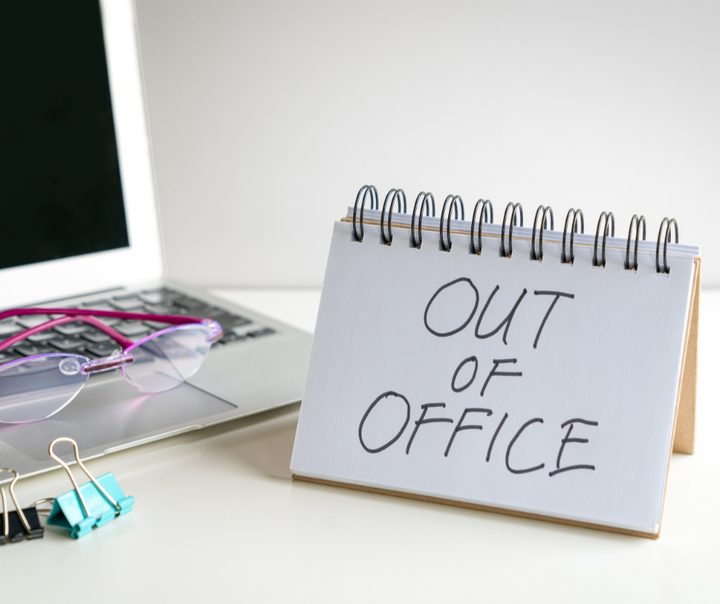 Out of office sign on a desk next to a laptop and office supplies, representing how to build business systems that allow a business to operate efficiently without constant owner involvement