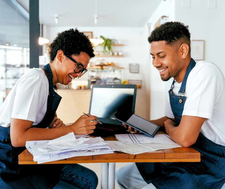 Two small business owners reviewing documents together to set up their Dun and Bradstreet business credit profile